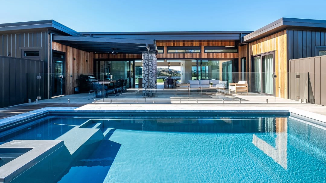 The Absolute 12.00m fibreglass swimming pool with a built-in spa is in the middle of the backyard, with white tiles and greenery surrounding it. The pool colour is shimmer white makes the fibreglass swimming pool glow in the sunlight. The Absolute 8.00m fibreglass swimming pool with a built-in spa is built at the heart of a contemporary design complex with white tiles surrounding it. The pool and built-in spa come in Graphite Grey colour, while the house is in yellow and brown.