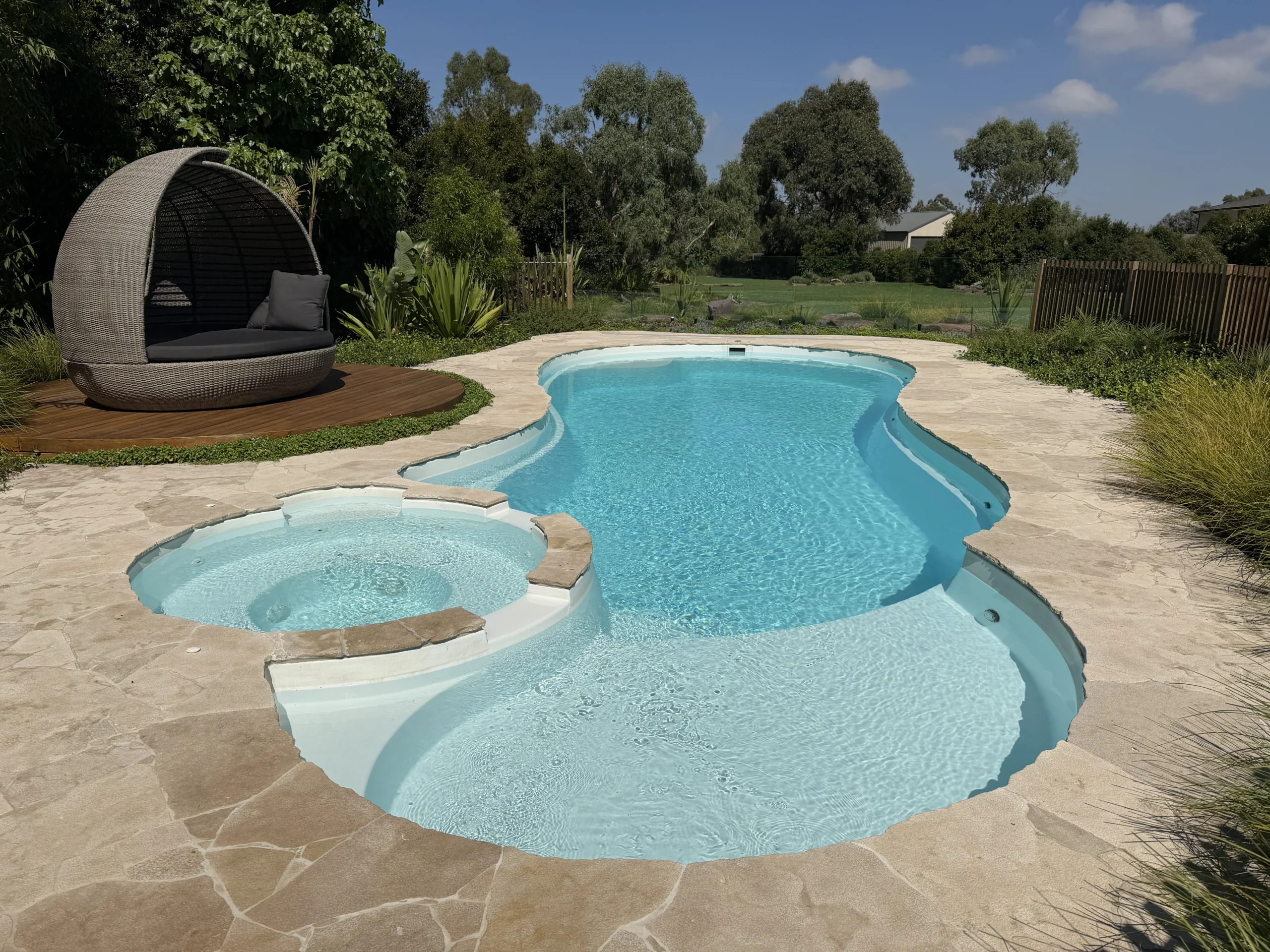 A beautiful swimming pool The Allure 12.15m in stunning Shimmer White colour in a large backyard with green scenery